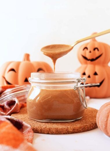 Pumpkin spice sauce on a gold spoon with pumpkins in the background.